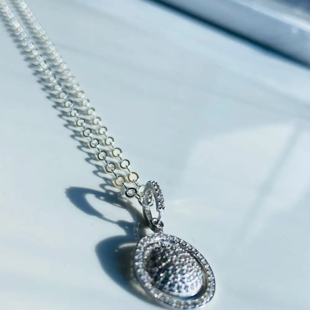 Silver chain necklace with white gold oval pendant encrusted with small clear stones. Jewellery silver jewellery Deep Shine Jewellers