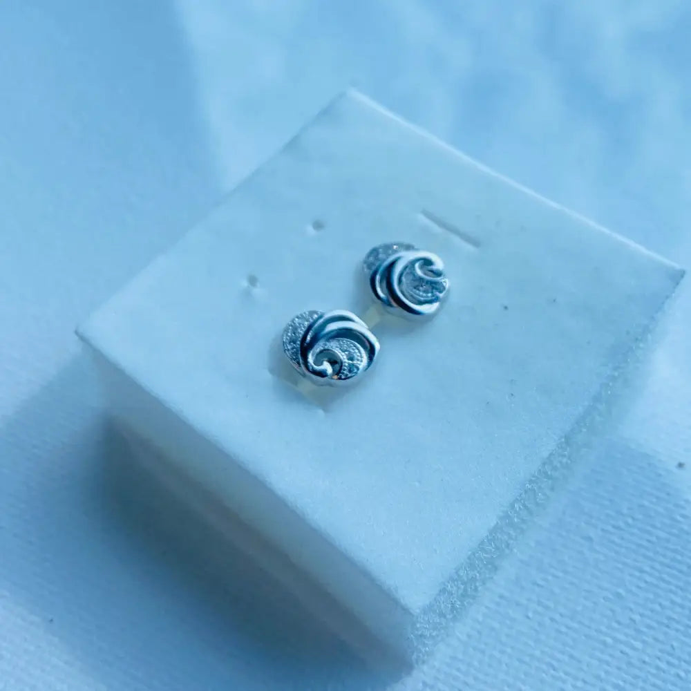 White gold silver stud earrings with wave design and clear gemstone accents