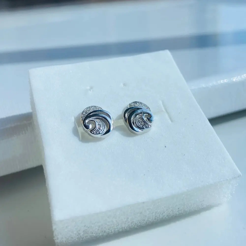 White gold silver stud earrings with swirling design and embedded gemstones for elegant style