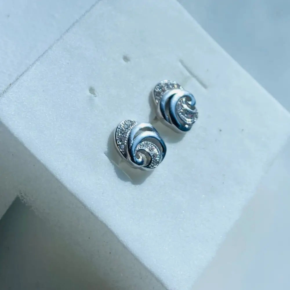 White gold silver stud earrings with swirling design and embedded gemstones for elegant style